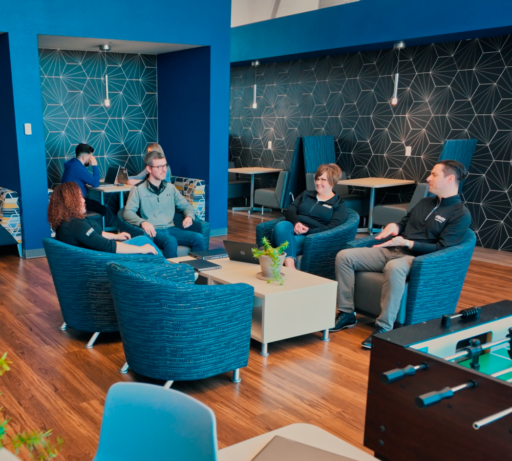 Four people sitting in a lobby talking together.