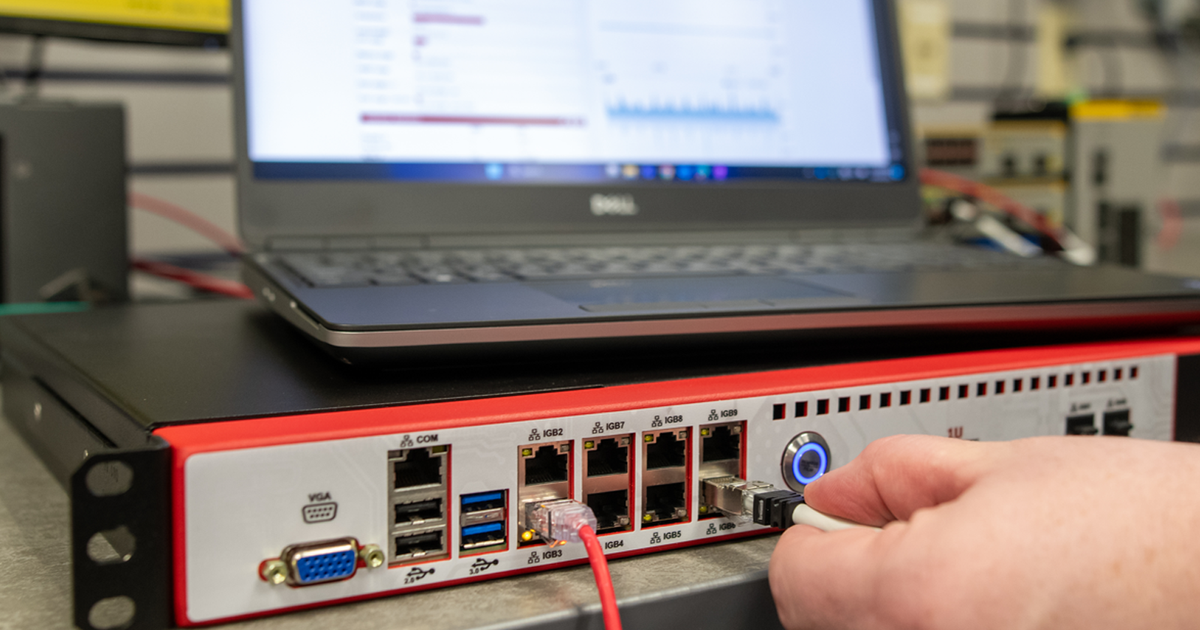 An employee plugging a cable into a ICS security device.
