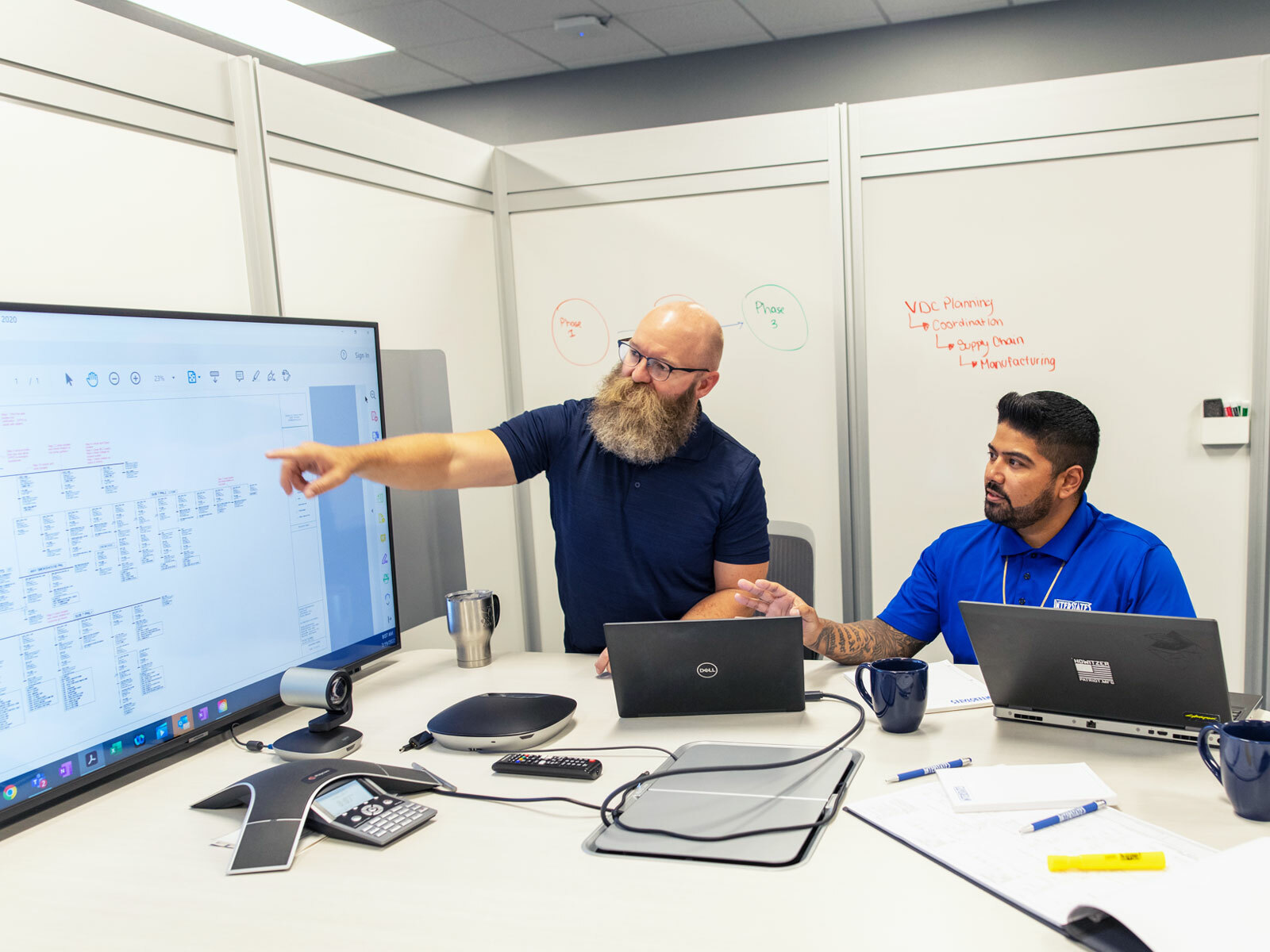 Two employees discussing information on a monitor.
