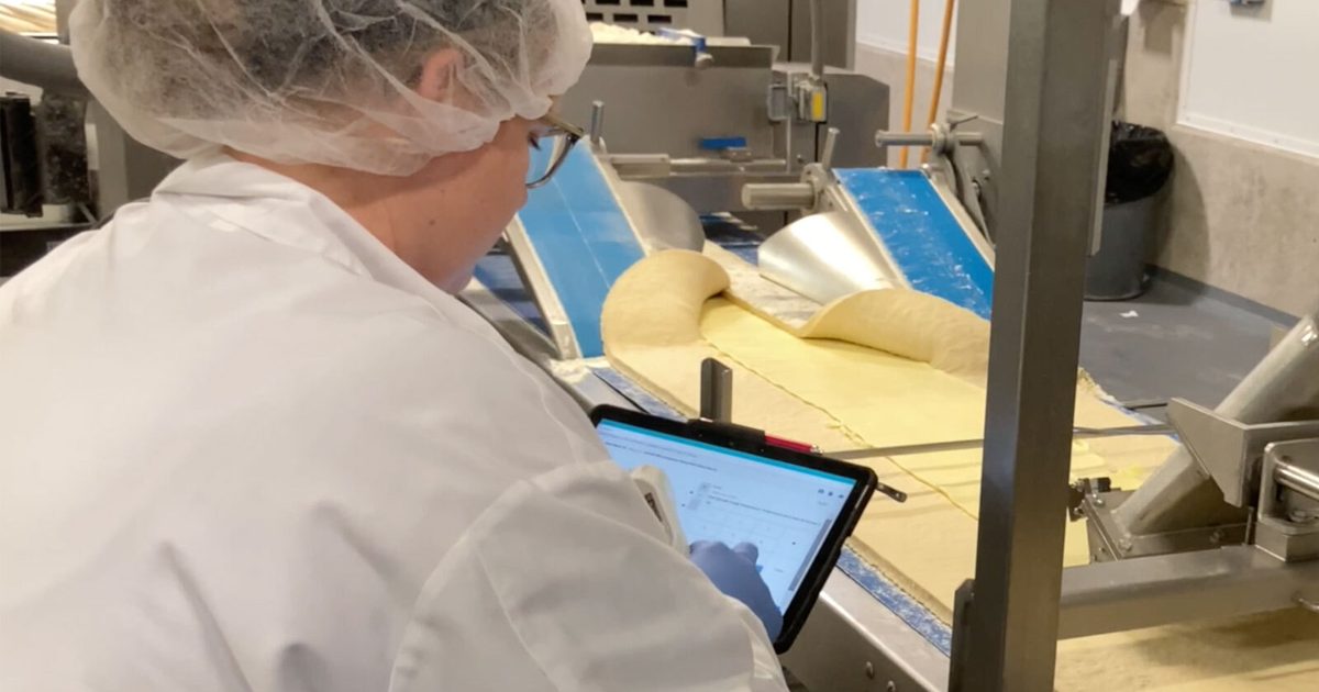 woman looking at a tablet in a food manufacturing facility that makes baked goods.