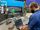 Systems analyst reviews networking information as a technician runs a press machine.