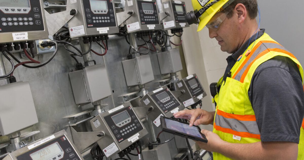 Individual in safety gear testing electrical equipment.