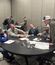Small group gathered around a table working on a hands-on challenge in a conference room.