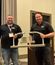 Two men stand in a conference room holding a metal award labeled "Industrialized Trailblazer Award."