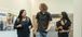 Three younger adults talking while walking down a hallway