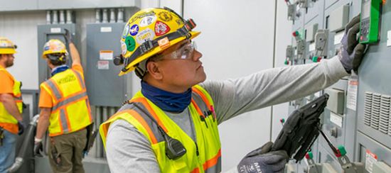 Man in PPE gear working on an electric room.
