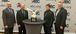 Four men dressed in suits posed in front of an ABC Eagle Award.