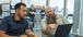 Two men talking and looking at a laptop.