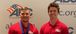 Two men wearing red polo shirts and medals.