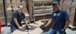 Woman and a man smiling packing a cardboard box.