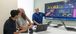 Three men viewing analytics data on a TV screen.
