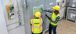 Two men wearing PPE gear viewing an automation screen.