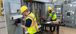 Two men working on an electrical cabinet.