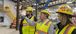 Three people wearing PPE gear viewing something in the distance.