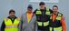 four people in high visibility vests standing together smiling