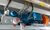 A close-up view of an industrial setup featuring a blue electric motor, hydraulic components, and electrical wiring.