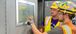 Two people in PPE gear looking at a human machine interface (HMI) in a plant.