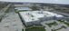 aerial view of a gray and red distribution plant and green grass around it.