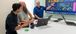 Three team members collaborating around a TV screen.