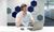 Man in a white polo shirt talks on a cellphone while working at a laptop in an office.