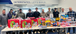 A group of 11 Interstates team members stands smiling behind a table filled with holiday-themed gift bags and toys.