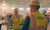 Two Interstates employees in hard hats and high-visibility vests discuss work inside a manufacturing facility
