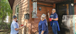 three women painting a brown house and smiling. They are wearing Interstates shirts.