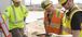 three construction workers looking at an iPad