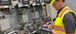 Man wearing PPE gear working on a tablet inside a facility.