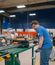 A man in a blue shirt and safety goggles turning a crank.