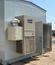 Exterior view of a gray modular electrical building with an attached HVAC system and an open access door under a clear blue sky.
