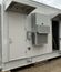 Exterior side view of a modular electrical building with multiple access doors, HVAC units, and equipment mounted along the wall.