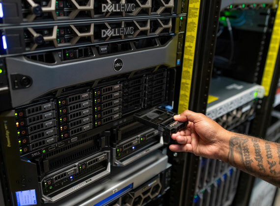 A employee pulls a tray out of a server rack.