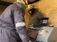 Two men wearing PPE working on laptops.