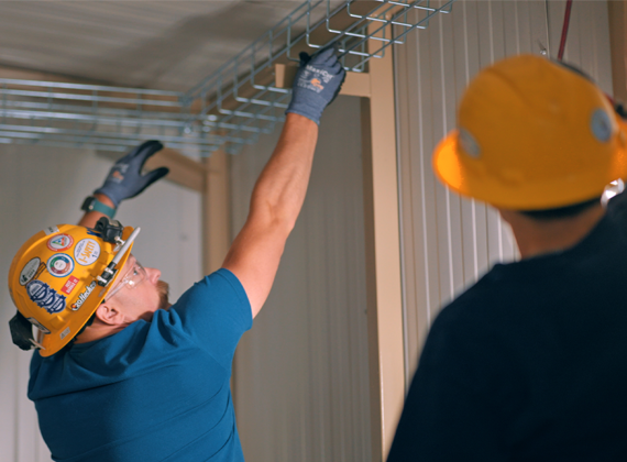 Two men installing cable trays.