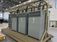 Large electrical equipment skid with multiple gray drive cabinets, heavy power cables, and overhead cable tray inside a manufacturing facility.