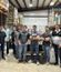 A group of workers stands together inside an industrial facility, posing for a photo among equipment and materials.