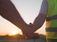 Two construction professionals in safety vests shaking hands at a job site during sunset