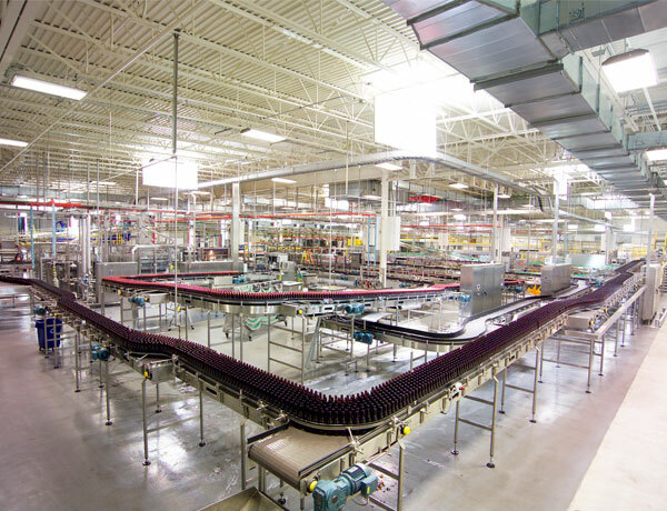 Inside of a facility that shows product being bottled and run on a conveyor belt. .