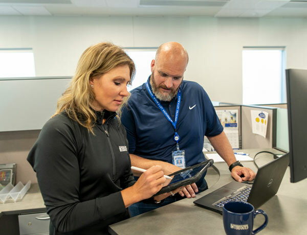 Two employees work on a tablet.
