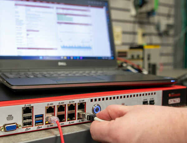 Cybersecurity analyst plugs a cable into a Industrial Control System Security Platform.