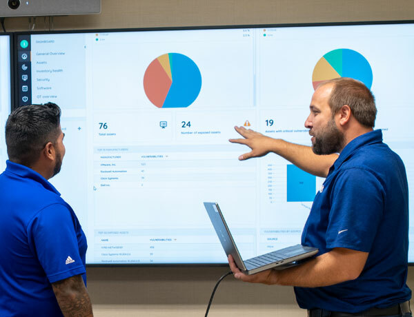 Two men looking at data and a pie chart on screen.