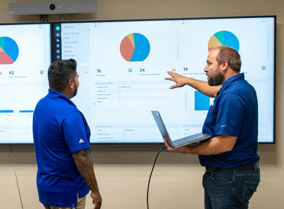 Two employees discuss a network topology diagram.