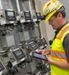 A employee in PPE monitors equipment in a facility.