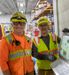 Two Interstates employees in safety gear next to an HMI monitor.