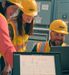three people looking at a laptop together in an industrial environment