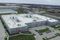 Aerial view of a gray and red distribution plant and green grass around it.