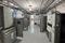 Interior of an industrial electrical room with rows of gray electrical cabinets, some doors open, overhead cable trays and conduit, and a clean concrete floor.