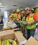 Four team members in construction PPE smiling at the camera while in line getting food.