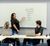 A woman presents Interstates core values on a whiteboard to a small team seated at laptops in a conference room.